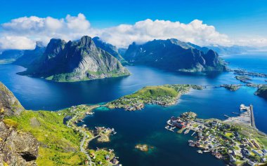 Büyüleyici bir Norveç fiyorduna yerleşmiş büyüleyici bir köyün nefes kesici hava manzarası. Berrak mavi suları çevreleyen yeşil tepeler ve görkemli dağlar. Reinebringen Lofoten Norveç Yazı