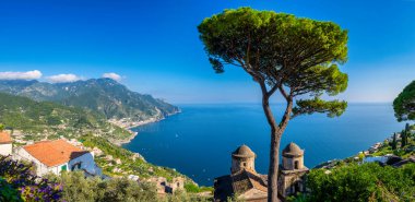 Uçurumların üzerinde canlı evler olarak Amalfi Sahili, berrak bir gökyüzünün altındaki sakin mavi denize bakıyor, yemyeşil ağaçlar bu İtalyan cennetinin doğal güzelliğini artırıyor. Ravello İtalya yazın