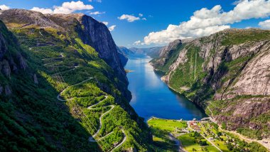 Norveç fiyordunun nefes kesen bir hava aracı görüntüsü, yükselen uçurumlar, yemyeşil alanlar ve fiyortun kristal berrak suları. Kjerag, Lysebotn, Lysefjorden, Norveç