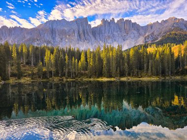 Dolomitler 'de sakin bir öğleden sonra, yüksek tepeler ve canlı sonbahar yapraklarıyla çevrili çarpıcı bir gölü gözler önüne seriyor. İtalya 'da sonbaharda Carezza Gölü veya Karersee Dolomitleri