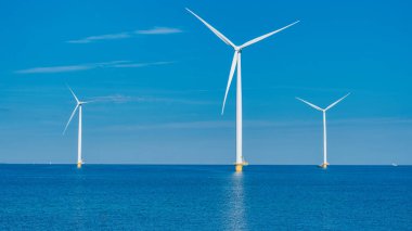 Hollanda 'daki Ijsselmeer' in sakin sularında dev rüzgar türbinleri güneş doğarken yenilenebilir enerjiyi kullanıyorlar. Mavi okyanusta 3 rüzgar türbini
