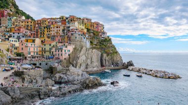 Renkli evler Cinque Terre 'deki Manarola İtalya' nın kayalık kayalıklarına tutunuyor. Işıldayan deniz canlı renkleri yansıtıyor, turistleri cazibesini ve güzelliğini keşfetmeye çağırıyor..