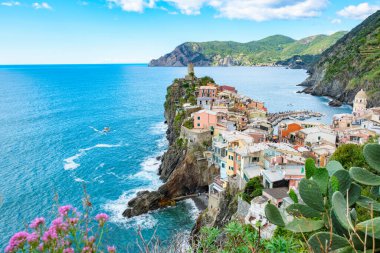 Colorful houses perched along the rocky cliffs of Vernazza Italy while waves lap gently at the shore. The breathtaking landscape of Cinque Terre showcases nature's beauty in Italy's Liguria region. clipart