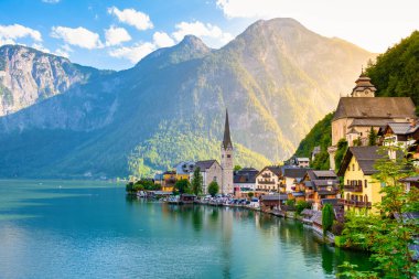 Yüksek dağların ortasında, büyüleyici evler göl kenarı boyunca canlı renklerle Avusturya Hallstatt 'ünü dolduruyor. Altın güneş ışığı sakin sularda dans eder, alacakaranlıkta resim gibi bir yansıma yaratır..