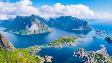 Göz kamaştırıcı bir Norveç fiyordunun nefes kesici hava manzarası. Berrak mavi suları çevreleyen yeşil tepeler ve görkemli dağlar. Reinebringen, Lofoten, Norveç