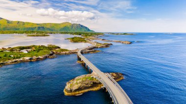 Norveç 'teki Atlantik Yolu Köprüsü' nün manzaralı bir manzarasında mavi okyanus ve çevresindeki adalar boyunca uzanan köprü görülüyor. Atlantik Okyanus Yolu Norveç