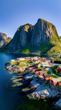 Norveç 'in Lofoten Adaları' ndaki dramatik dağların arasına yerleşmiş bir köy. Kırmızı çatılı evler kayalık kıyı şeridine tünemiş ve yemyeşil ile çevrili. Yazın Hamnoy Lofoten Norveç