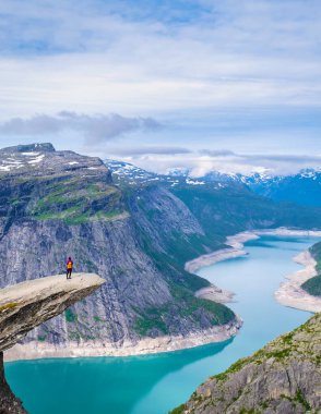Norveç 'in Trolltunga kentinde yalnız bir kadın yürüyüşçü duruyor. Norveç' te turkuaz bir fiyorda tepeden bakan dramatik bir uçurum. Manzaranın enginliği nefes kesici..