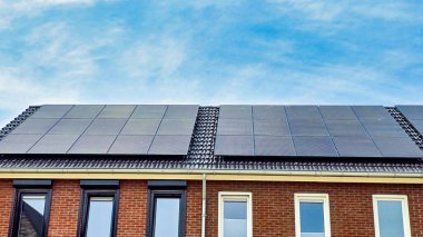 Hollanda 'da güneşli bir gökyüzüne karşı çatıdaki siyah güneş panelleri siyah güneş panelleri olan yeni binayı kapatıyor. Zonnepanelen, Zonne Energie, Çeviri: Güneş Paneli, Güneş Enerjisi