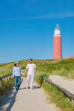 Bir çift erkek ve kadın Texel Deniz fenerini ziyaret ediyor, çarpıcı kıyı manzarasının ve çarpan dalgaların sesinin keyfini çıkarıyorlar..