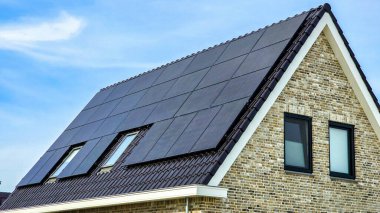 Çatıda siyah güneş panelleri olan yeni yapılmış evler mavi güneşli gökyüzüne karşı siyah güneş panelleri olan yeni binaları kapatıyorlar. Zonnepanelen, Zonne Energie, Çeviri: Güneş Paneli, Güneş Enerjisi