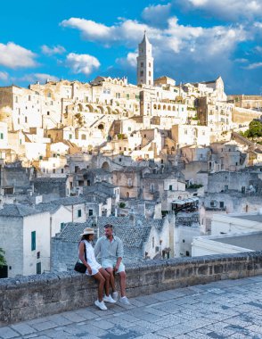 Bir çift, gün batımının altın ışığının tadını çıkarırken antik Matera, Puglia Sassi 'ye hayran kalıyor. Tarihi binalar yazın nefes kesici bir zemin oluşturuyor.