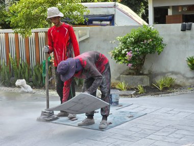 Pattaya, Tayland 29 Kasım 2024, iki zanaatkar titiz bir şekilde dekoratif beton kullanıyor, teknikleri benzersiz yüzeyler yaratmak için gereken beceri ve beceriyi vurguluyor..