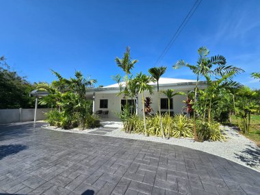 Yeşillik ve tropik bitkilerle çevrili canlı, modern bir ev güzel damgalanmış beton bir garaj yolu sergiliyor. Modern bir aile evi olan Tayland Suburban bölgesi.