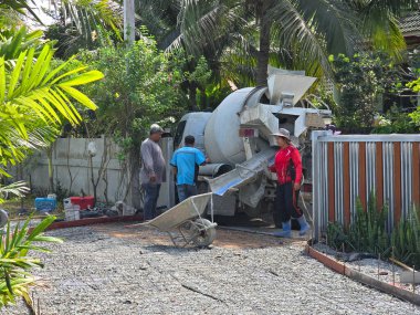 29 Kasım 2024 'te Pattaya, Tayland' da işçiler güzel damgalanmış bir yüzeye beton döküp hazırlanmakla meşguller. Güneş ışığı çevreyi aydınlatır.