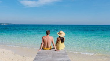 A couple enjoys a peaceful moment together on the pristine beach of Koh Munnork Island in Thailand. clipart