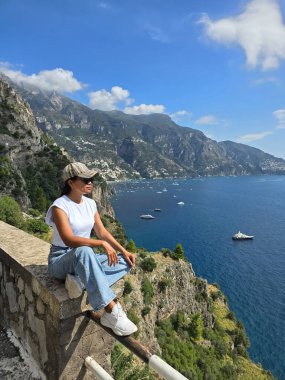 Amalfi Sahili 'ni canlı evler olarak ziyaret eden Asyalı bir kadın bu İtalyan cennetinin berrak gökyüzünün altındaki sakin mavi denizi seyrediyor. İtalya 'da yaz aylarında kadın turist