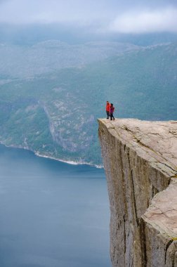 Bir çift, bir uçurumun kenarında durur ve sisle kaplanmış Norveç fiyortlarının nefes kesici manzarasını seyrederler. Norveç 'in önceki bölümlerinde, çeşitli erkek ve kadınlar tatilde.