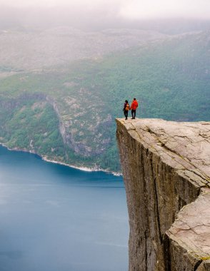 Norveç 'te dramatik bir uçurum olan Preikestolen' in kıyısında duran bir çift kadın ve erkek fiyordun engin genişliğine bakıyorlar. Preikestolen, Norveç Yazları Erkek ve Kadın Coupe