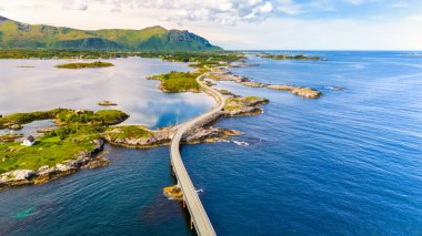 Norveç kıyı şeridi boyunca turkuaz suların üzerindeki dolambaçlı yolun havadan görünüşü, çarpıcı bir manzarada küçük adaları birbirine bağlıyor. Yazın Atlantik Okyanusu Yolu Norveç