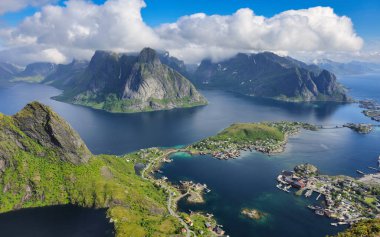 Huzurlu suların üzerinde görkemli dağlar yükselirken, kıyı şeridi boyunca uzanan büyüleyici köyler güneş ışığıyla yıkandı. Reinebringen Lofoten Adaları Norveç