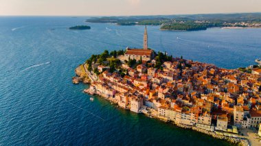 Antik Rovinj Hırvatistan kasabasına bakan gök mavisi dalgaları, yüksek kilise tarafından taçlandırılan renkli binalara nazikçe sarılıyor. Bu resim gibi manzara, kıyı yaşamının cazibesini yansıtıyor. 