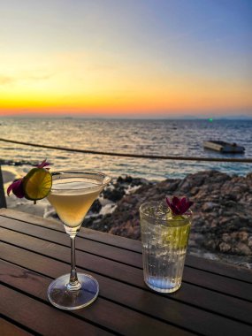 Koh Munnork Adası 'nda okyanusun üzerinde çarpıcı bir gün batımını izlerken nefis kokteyller içmek. Gökyüzünün canlı renkleri mükemmel bir tropikal akşam deneyimini yansıtır..