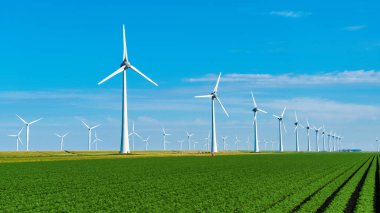 Büyük yel değirmeni türbinleri, Hollanda 'daki yemyeşil alanlar arasında yenilenebilir enerjiyi kullanarak zarifçe dönüyor. Noordoostpolder Flevoland 'da yeşil enerji, sıfır emisyon