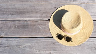 Güneş şapkası, şık güneş gözlükleriyle eşleştirilmiş ahşap bir yüzeyde duruyor. Tayland 'ın Rayong kentindeki Koh Munnork Adası' nda sakin bir günün özünü yakalıyor. Rahatlamanın doğanın güzelliğiyle buluştuğu yerde..