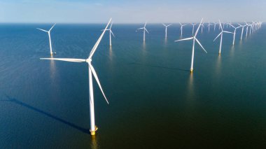 Hollanda 'da mavi gökyüzü yeşil enerji kavramına sahip elektrik üreten bir dizi yel değirmeni türbini.
