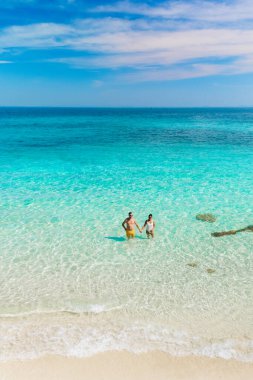 A couple explore the stunning turquoise waters surrounding Koh Munnork Island in Rayong, Thailand. Bright sun and soft sand create an idyllic tropical getaway, perfect for relaxation and adventure. clipart