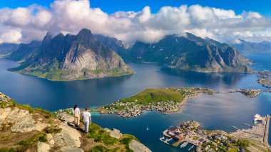 Norveç 'teki Lofoten Adaları' nın çarpıcı panoramik manzarası engebeli dağları, derin fiyortları ve büyüleyici köyleri gözler önüne seriyor. Reinebringen Lofoten Norveç 'e bakan bir uçurumda iki kişi duruyor.