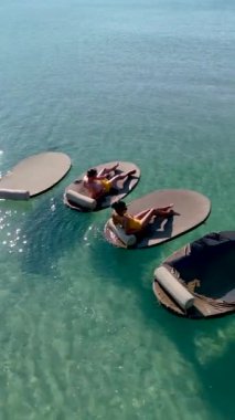 Koh Kood Adası 'nın berrak sularında yüzen paspasların üzerinde uzanan huzurlu anlar. Tropikal titreşimler ve güneş ışığının tadını çıkar. Tayland 'da tatilde olan çeşitli erkek ve kadınlar.