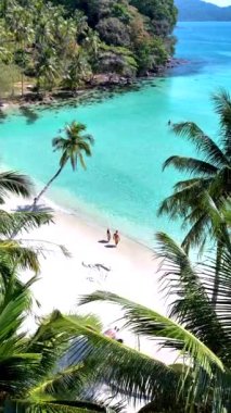 Koh Kood Adası 'nın berrak sularının yumuşak ve kumlu sahillerle buluştuğu sakin kıyılarını deneyin. Güneşlenirken sallanan avuçların altında rahatla, Tayland 'da tatilde olan bir çift.