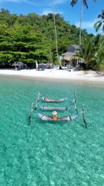 Koh Kood Adası 'nın tropikal cennetinde keyif çatın. Sakin hamakların mavi suların üzerinde yavaşça sallandığı yerde. Tayland 'da tatilde olan çeşitli erkek ve kadınlar.
