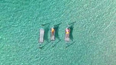 Koh Kood Adası 'nın dinginliğini hissedin. Canlı hamaklar, turkuaz okyanusun üzerinde hafifçe sallanıyor. Tayland 'da balayına çıkan çeşitli erkek ve kadınlar.