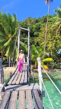 Tayland, Koh Kood 'da huzurlu bir günün tadını çıkar. Yeşillik ve berrak sularla çevrili büyüleyici bir ahşap köprüde gezinen kadın. Bu tropikal bölgede doğa ve sükunet boldur.