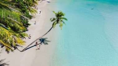 İnsanlar, güneş batmaya başladığında, Tayland 'ın el değmemiş kumlu kıyıları boyunca sakin bir yürüyüşün tadını çıkarıyorlar. Kristal berrak sular yavaşça dalgalanır, sakin bir atmosfer sunar..