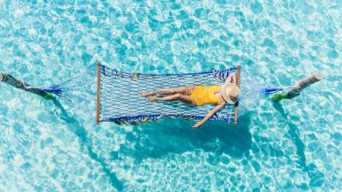 Bir kadın, parlak turkuaz okyanusun üzerinde asılı bir hamakta huzurlu bir öğleden sonranın tadını çıkarırken huzurlu bir an başlıyor. Güneş ışığı su yüzeyinde dans ediyor, Koh Kood 'un güzelliğini arttırıyor..