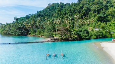 Koh Kood 'un ışıl ışıl turkuaz sularında, canlı yeşillikler ve yumuşak kumlu kıyılarla çevrili, okyanusta bir hamakta bir çift. Tayland 'ın göbeğinde mükemmel bir tropikal kaçış.