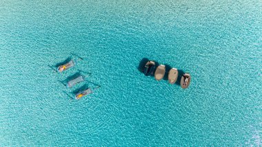 Güneş banyosu, Koh Kood, Tayland 'ın canlı turkuaz sularında rahat bir şekilde yüzer. Parlak güneşin altında sakin bir öğleden sonranın tadını çıkarırlar. Okyanusta bir çift hamak.