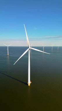 Görkemli rüzgar türbinleri Hollanda 'nın sakin suları üzerinde yükseliyor ve rüzgarı etkili bir şekilde temiz enerjiye dönüştürüyor. Huzurlu manzara sürdürülebilirlik ve yeniliğe olan bağlılığını gösteriyor.