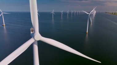 Rüzgar türbinleri Hollanda topraklarında zarifçe dönüyor, yenilenebilir enerji potansiyeli sergiliyorlar. Okyanustaki yel değirmeni parkı, yel değirmeni türbinlerinin yeşil enerji üreten hava aracı görüntüsü.