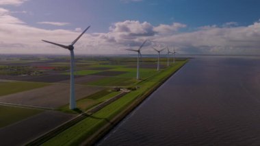 Görkemli rüzgar türbinleri Hollanda 'nın dingin arka planına, okyanustaki yel değirmeni parkına, yeşil enerji üreten yel değirmeni türbinlerine karşı dik dururlar. 