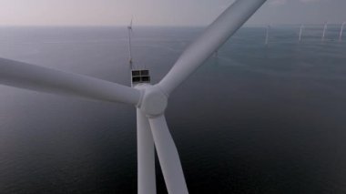 Ufukta dönen etkileyici yel değirmeni türbinlerine bakın. Güçlü rüzgarlardan yenilenebilir enerji elde ediyorlar. Bu çarpıcı görüntü Hollanda 'daki sürdürülebilir enerjinin özünü yakalar..