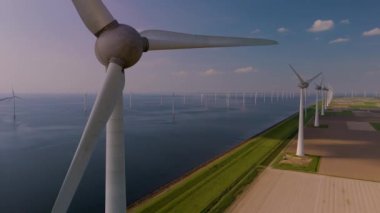 Hollanda 'daki su boyunca yüksek rüzgar türbinleri. Okyanustaki yel değirmeni parkı, yel değirmeninin hava görüntüsü yeşil enerji üreten türbinler, deniz yel değirmenleri