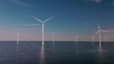 Görkemli yel değirmeni türbinleri Hollanda 'nın sakin suları üzerinde doğal enerjilerini kullanarak dimdik duruyorlar. Bu yapılar, sürdürülebilir uygulamalara ve yeniliğe olan bağlılığı sembolize etmektedir..