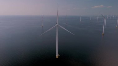 Dev rüzgar türbinleri Hollanda 'nın sakin suları üzerinde zarifçe dönerek yenilenebilir enerjiden faydalanıyor. Doğa ve teknoloji, sürdürülebilir güç üretiminin bu çarpıcı gösterisinde birleşiyor..