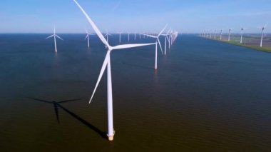 Nefes kesici bir manzara, Hollanda 'nın sakin suları üzerinde zarifçe dönen sayısız yel değirmeni türbini sergiliyor. Bu etkileyici manzara, yenilenebilir enerjilerin geleceği şekillendirmedeki rolünü vurguluyor..