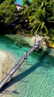 Koh Kood Tayland 'ın huzurunu yaşayın. İki figür, kırsal ahşap bir köprüde huzurlu bir gezinti yapıyor..